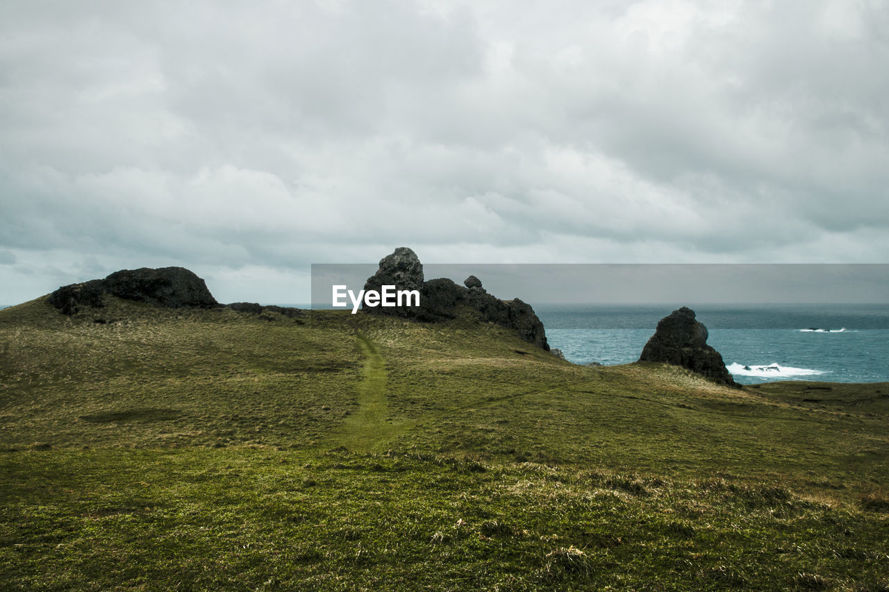 SCENIC VIEW OF SEA BY LAND AGAINST SKY