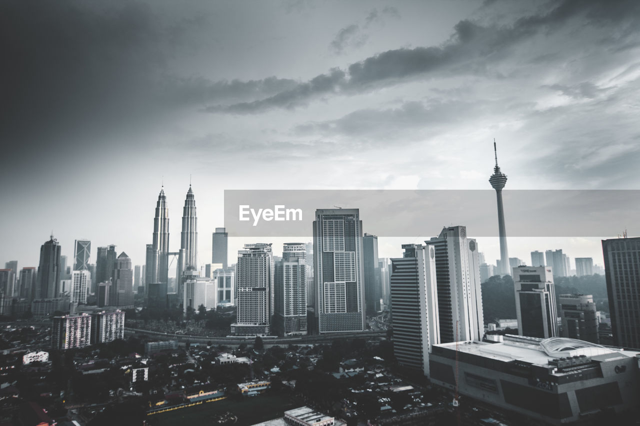 Kuala lumpur tower and petronas towers in city against sky during dusk