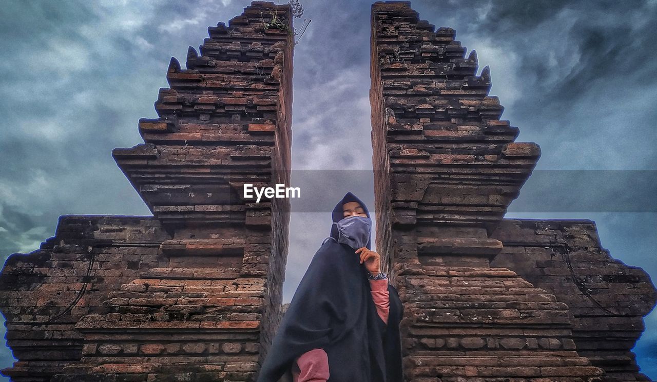 LOW ANGLE VIEW OF MAN AGAINST TEMPLE BUILDING