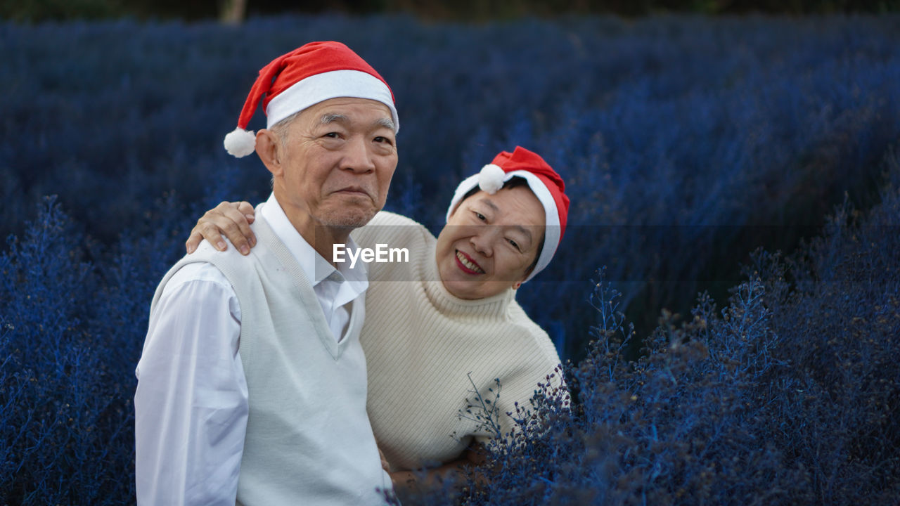 Portrait of a smiling asian senior couple christmas seasonal holiday red and white magic purple