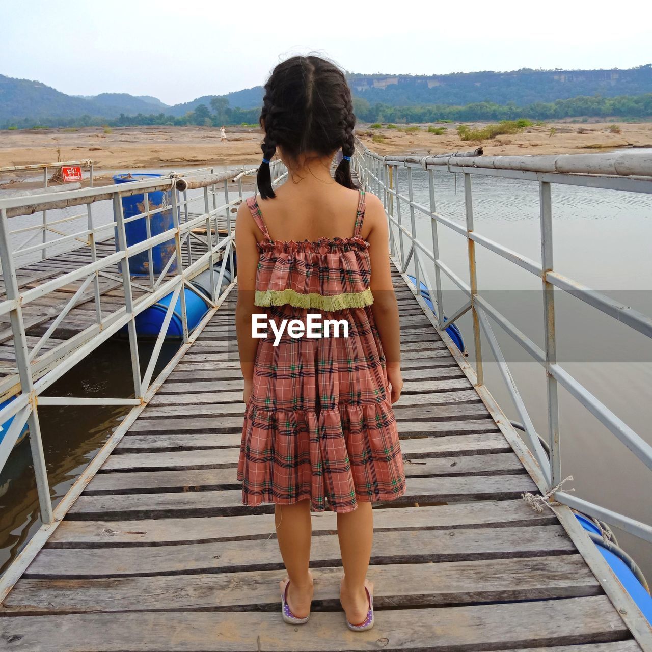 Rear view of girl standing on footbridge over sea