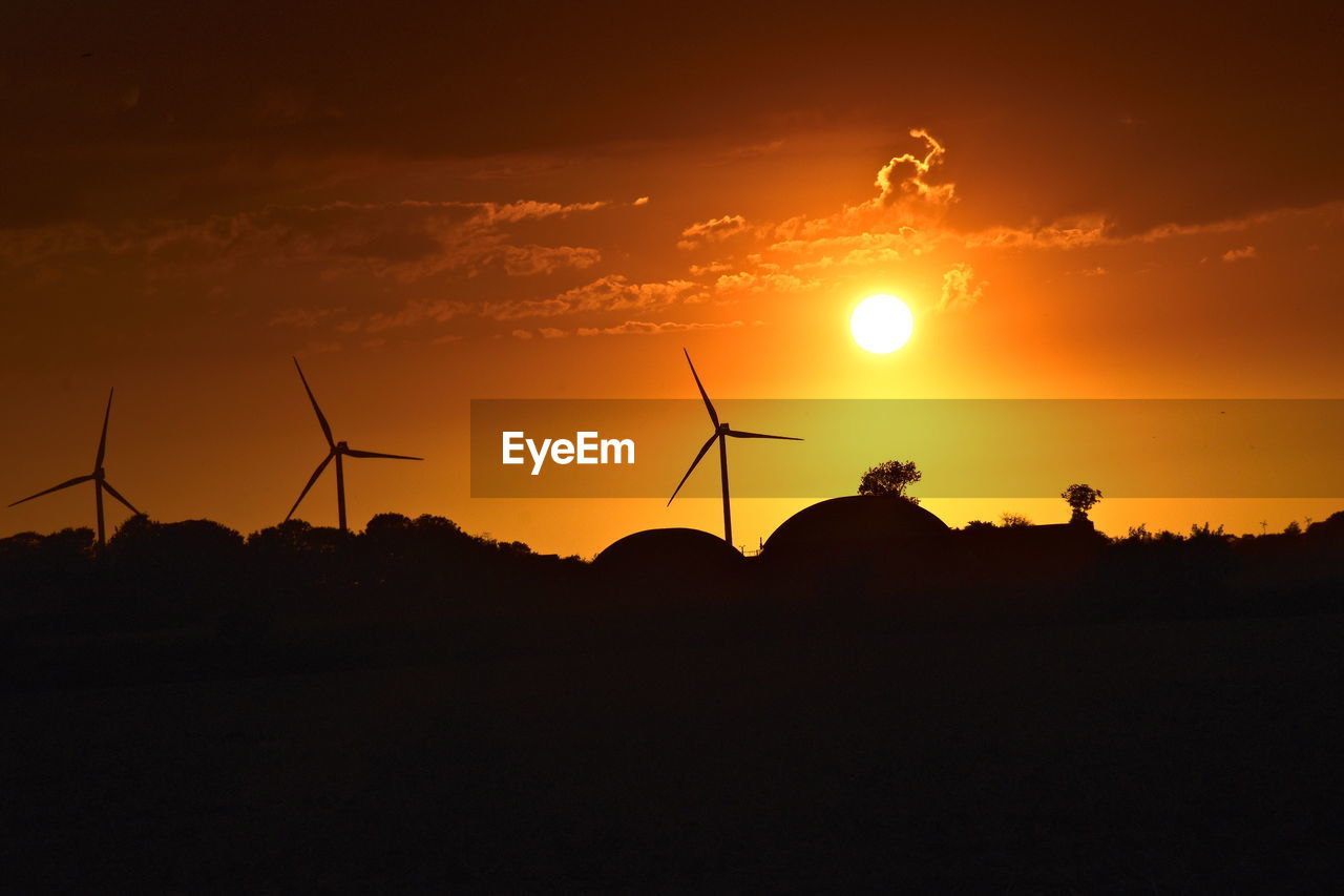 SILHOUETTE OF WIND TURBINES ON FIELD AGAINST SKY DURING SUNSET