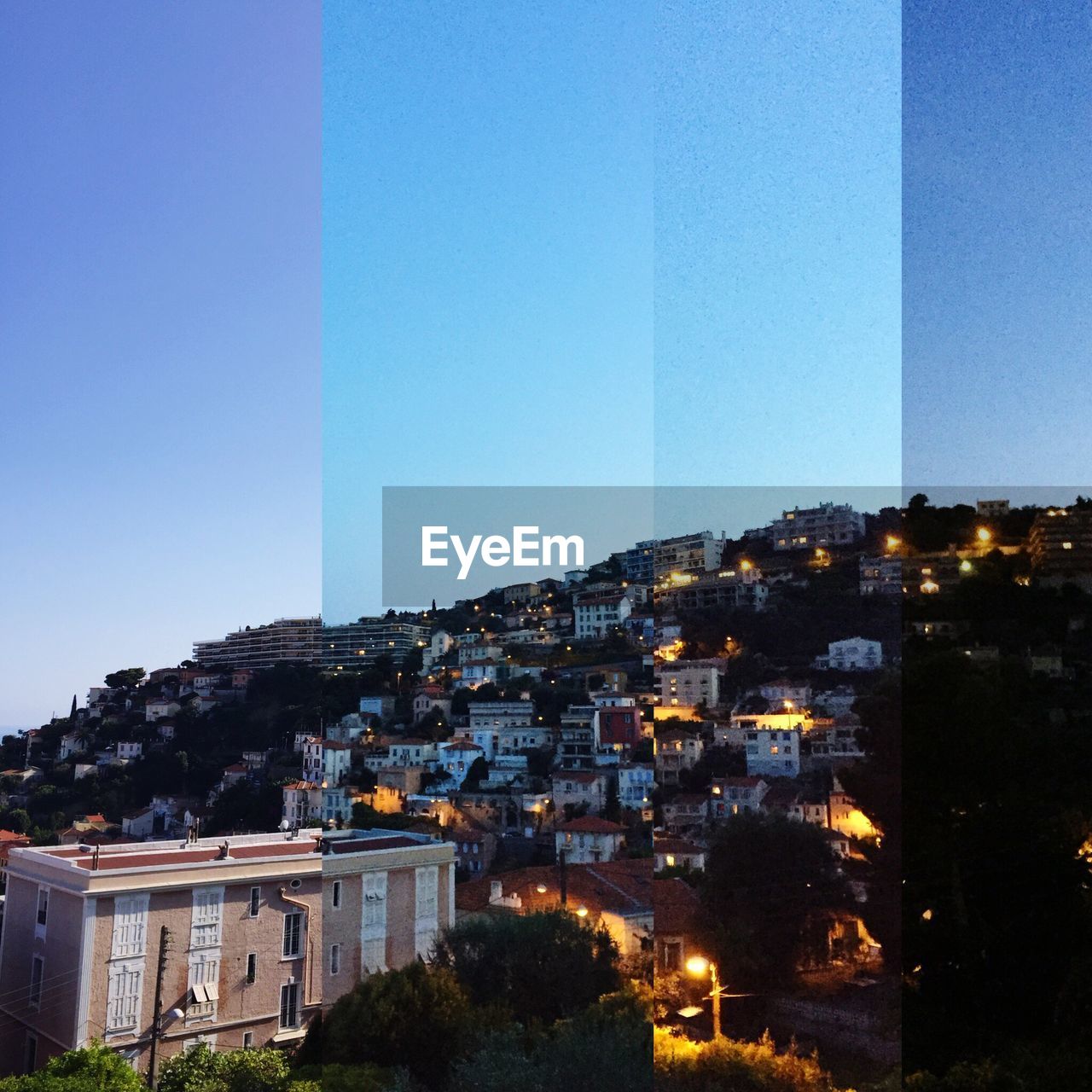 Illuminated residential houses on hill against sky