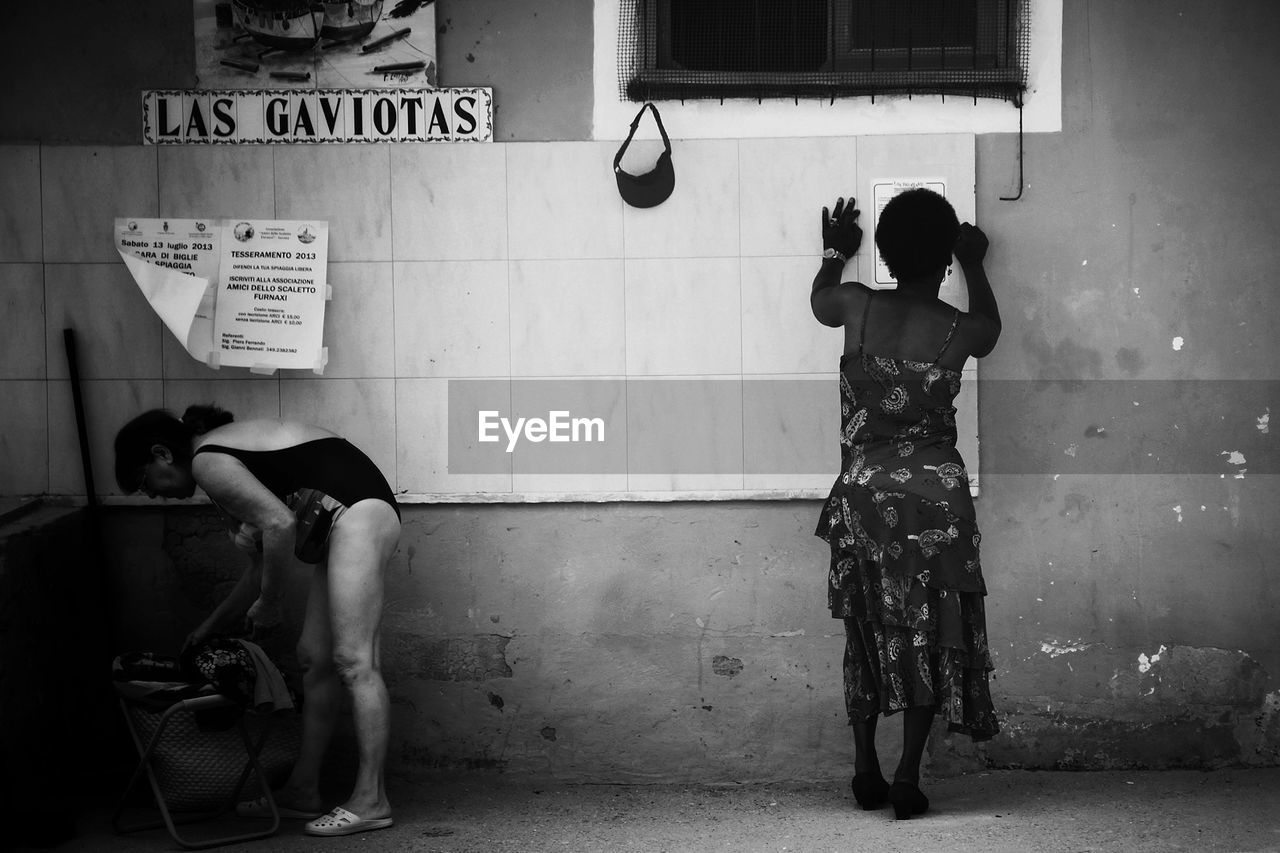 Full length of women standing against wall