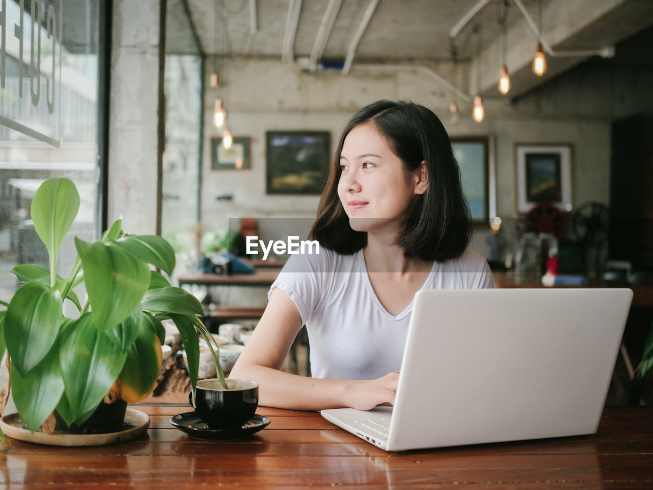 Smiling young businesswoman using laptop on table at cafe