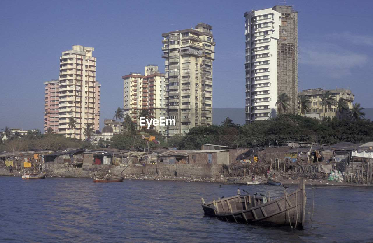 buildings by river against sky in city