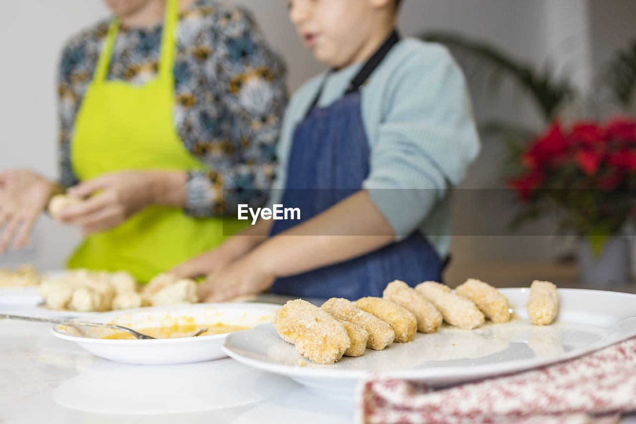 Mother and son making croquettes in the kitchen