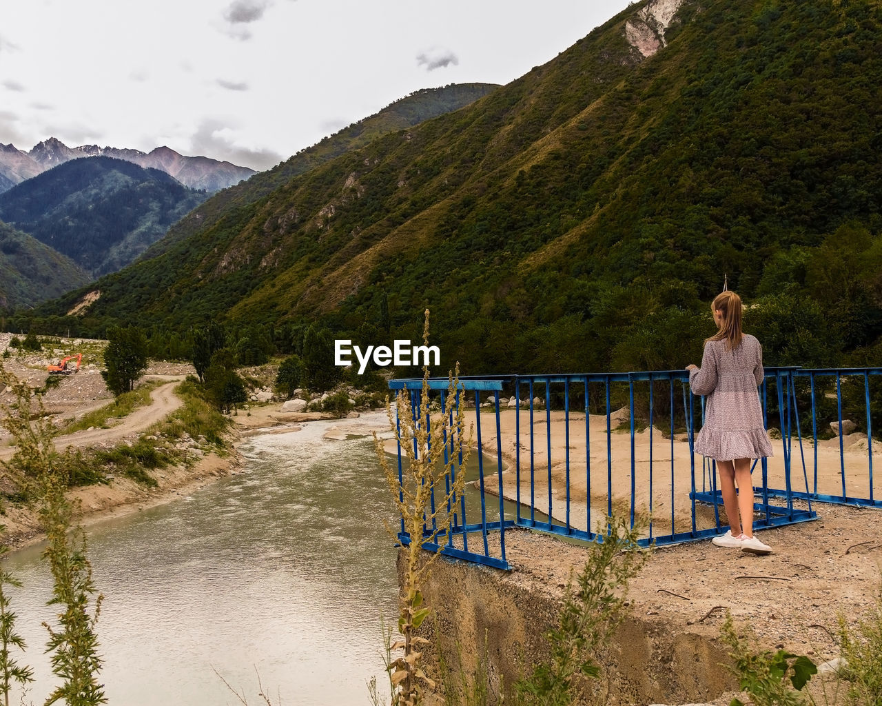 Rear view of woman standing by railing against mountains