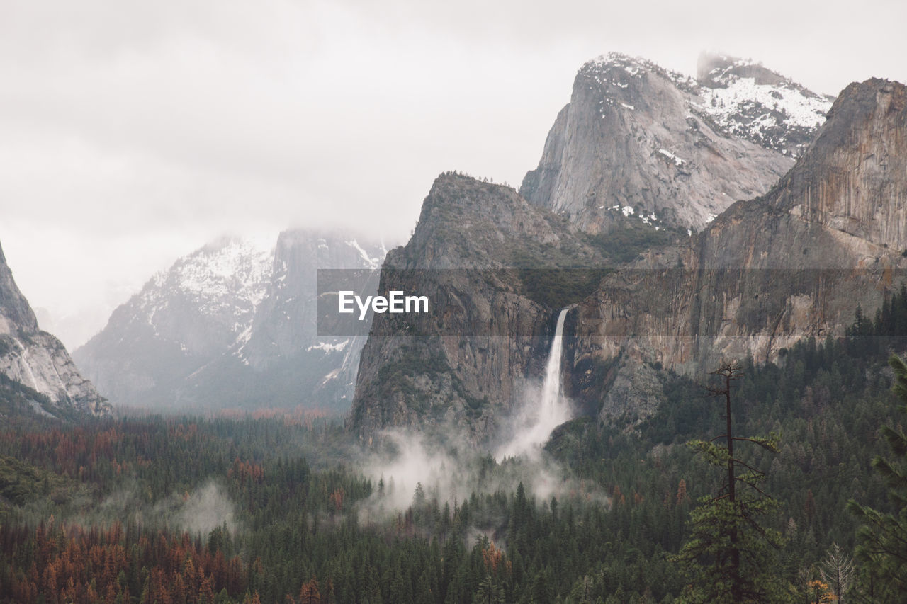 Scenic view of waterfall and mountains against sky