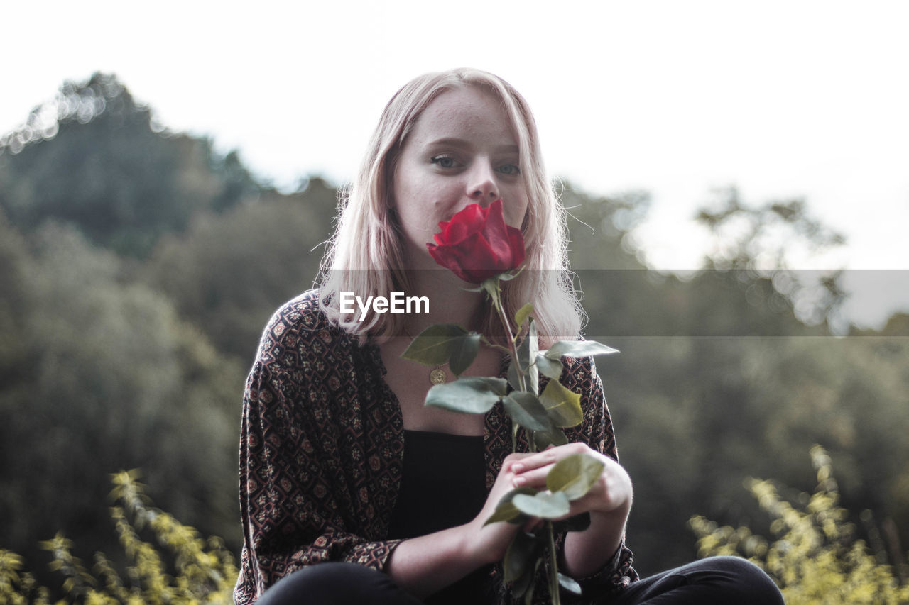 Portrait of smiling young woman holding red rose