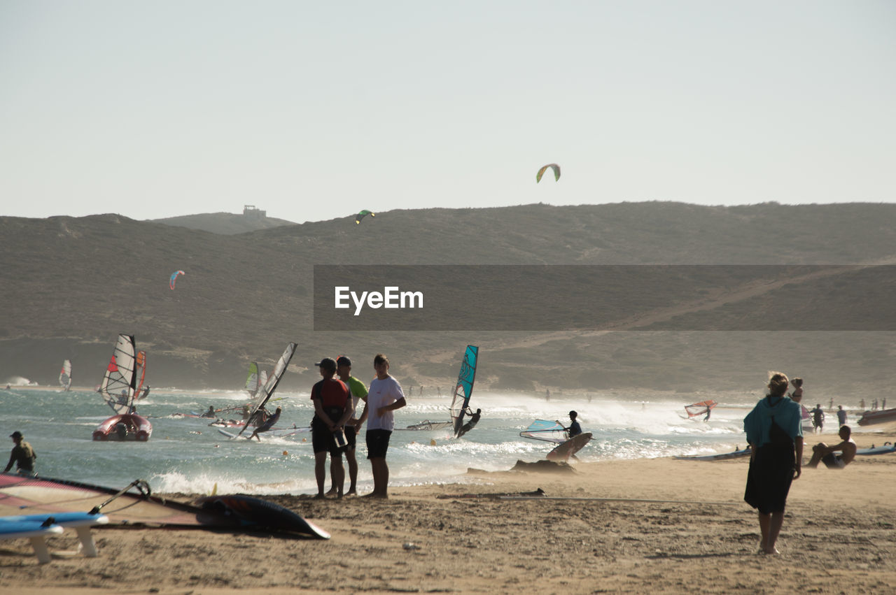 PEOPLE AT BEACH AGAINST SKY