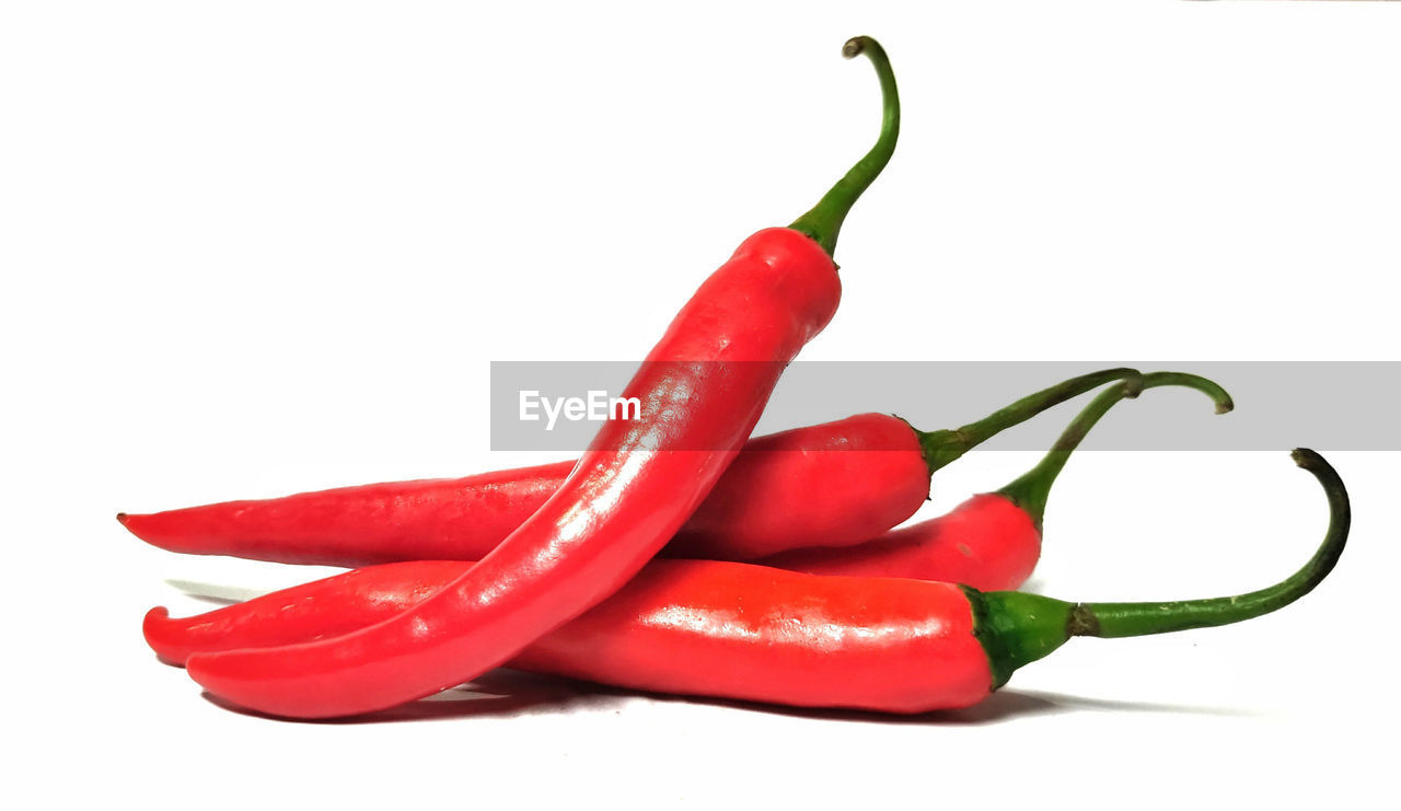 CLOSE-UP OF CHILI PEPPERS AGAINST WHITE BACKGROUND