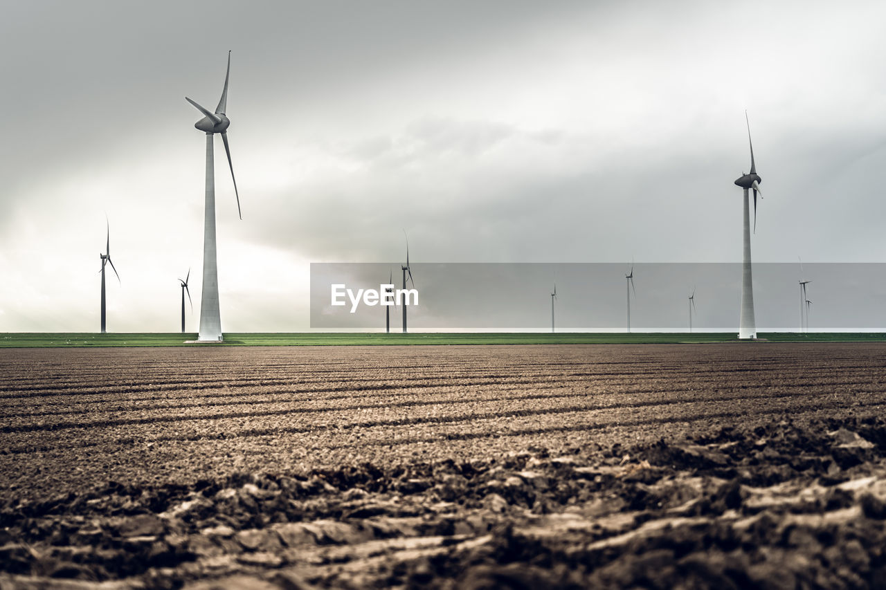 Wind turbines on land against sky