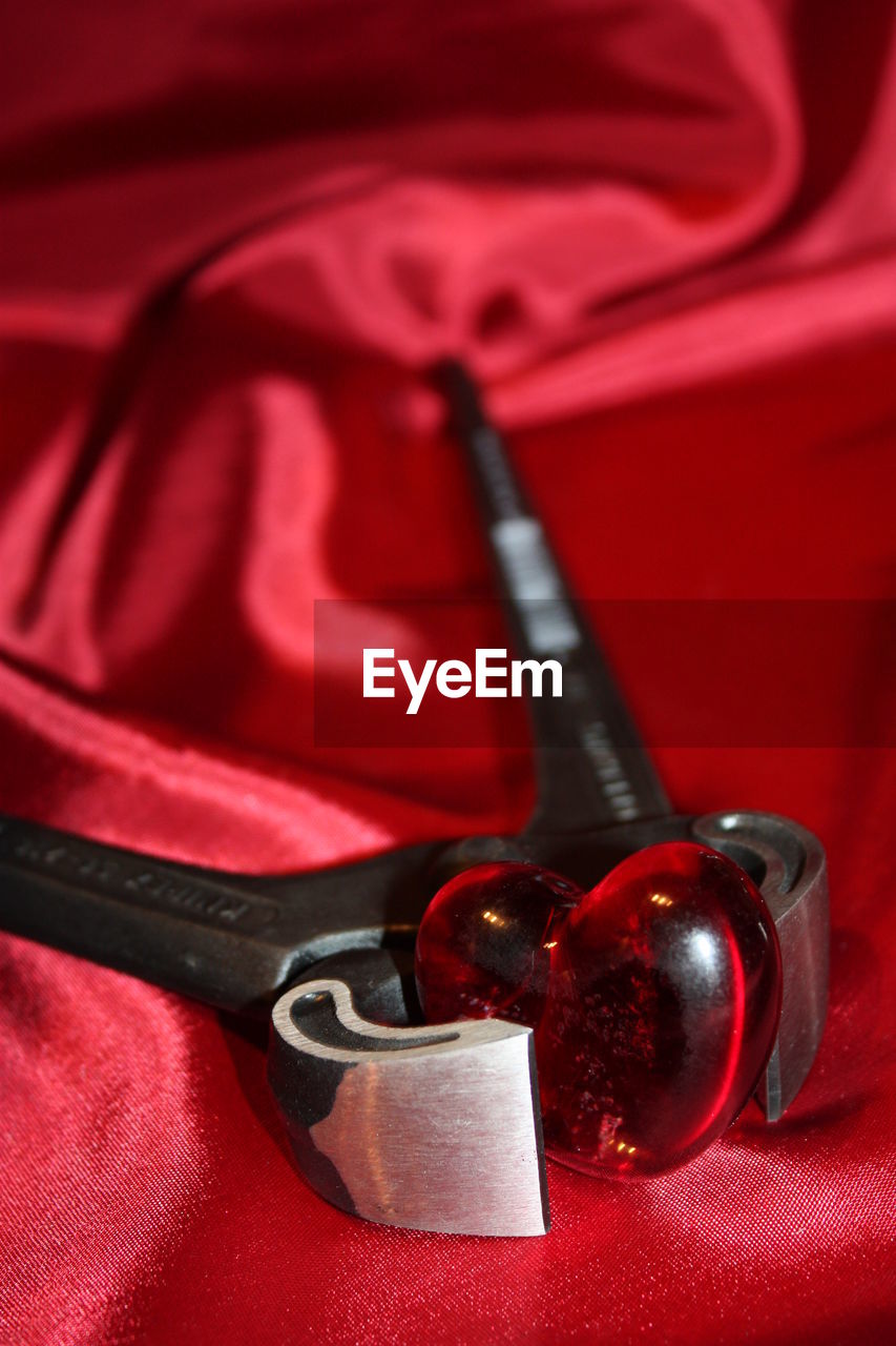 Close-up of heart shape and pliers on red textile