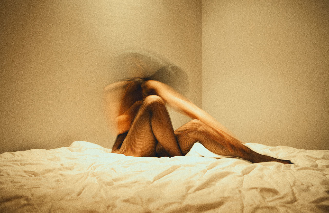 Multiple exposure of naked woman sitting on bed in room