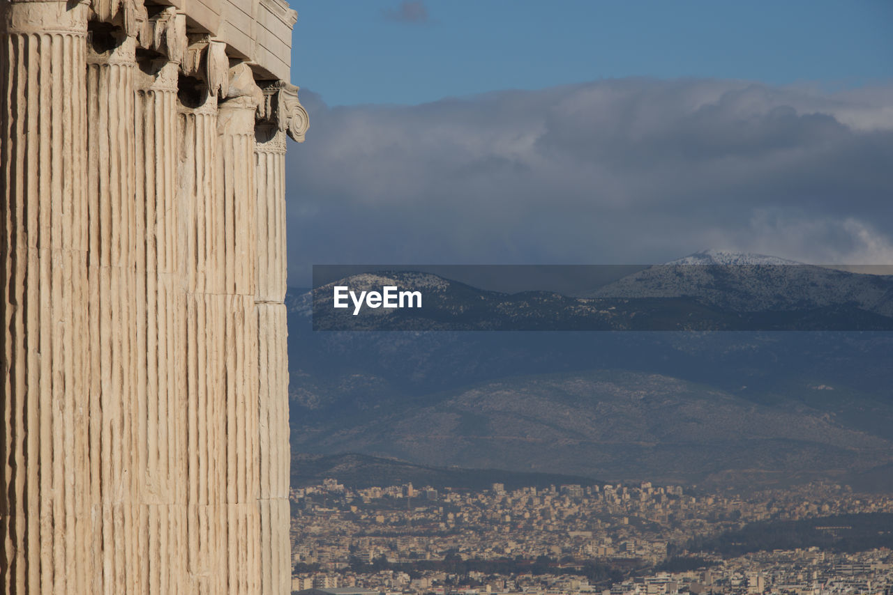 Architectural columns in a row by mountains against sky