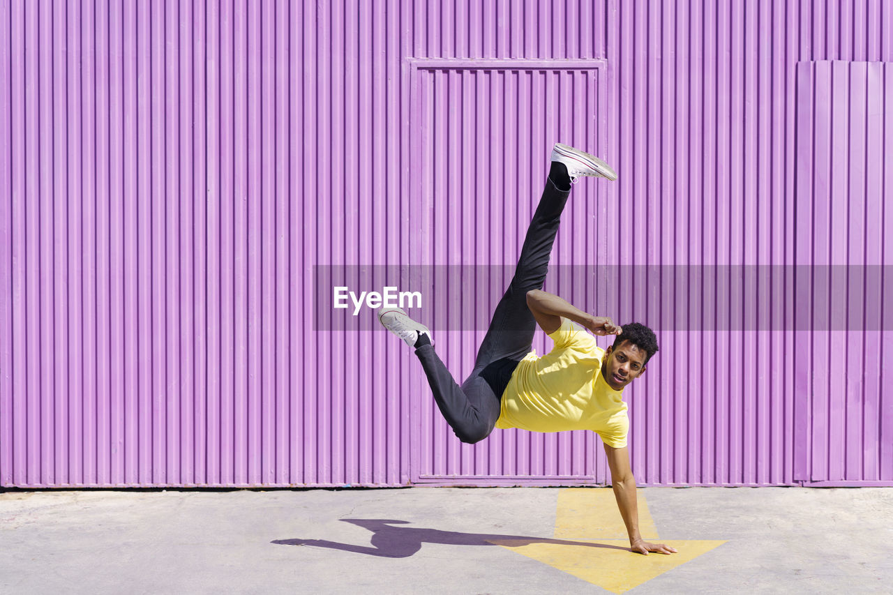 Man doing handstand on footpath during sunny day