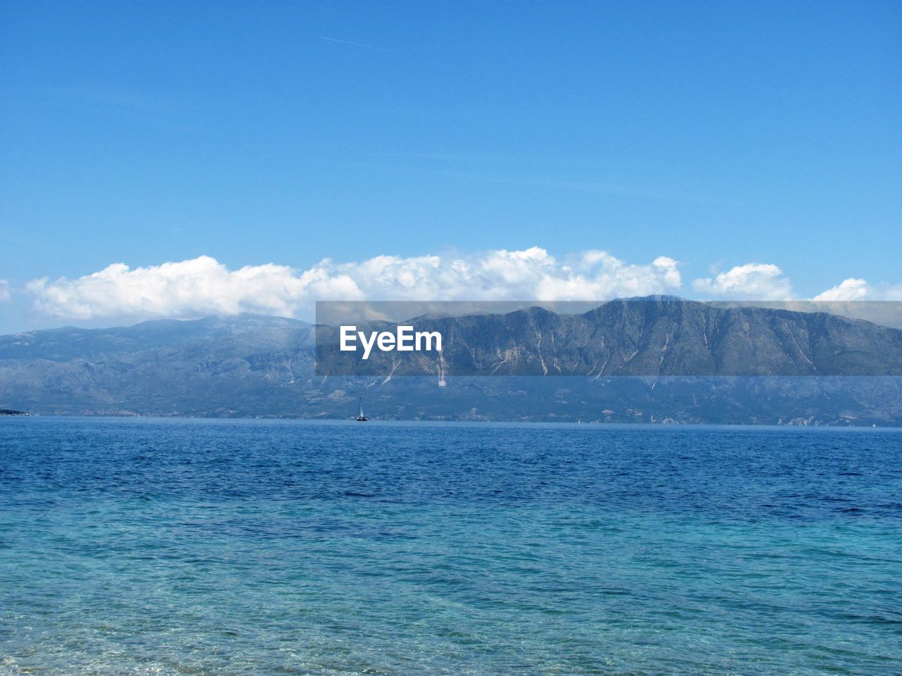 Scenic view of sea and mountains against blue sky