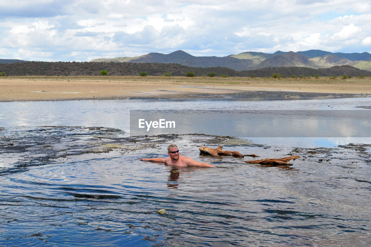 Full length of shirtless man swimming at the hot springs of lake magadi, kenya 