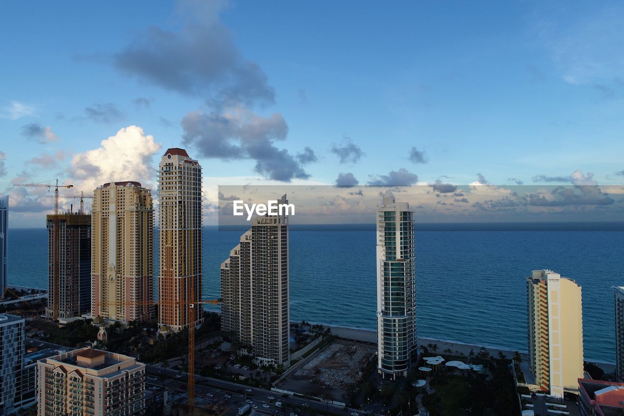 Modern buildings by sea against sky in city