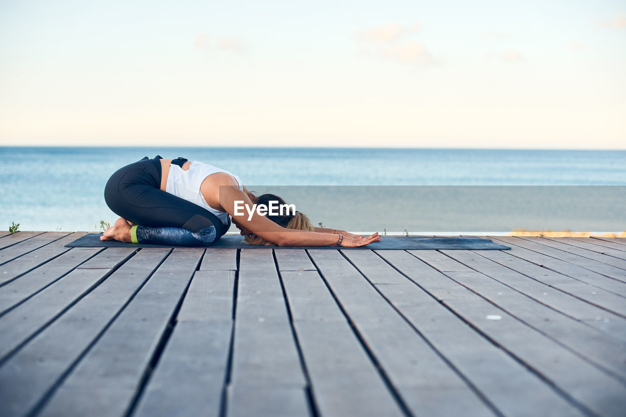 MAN SITTING ON CHAIR AT SEA SHORE