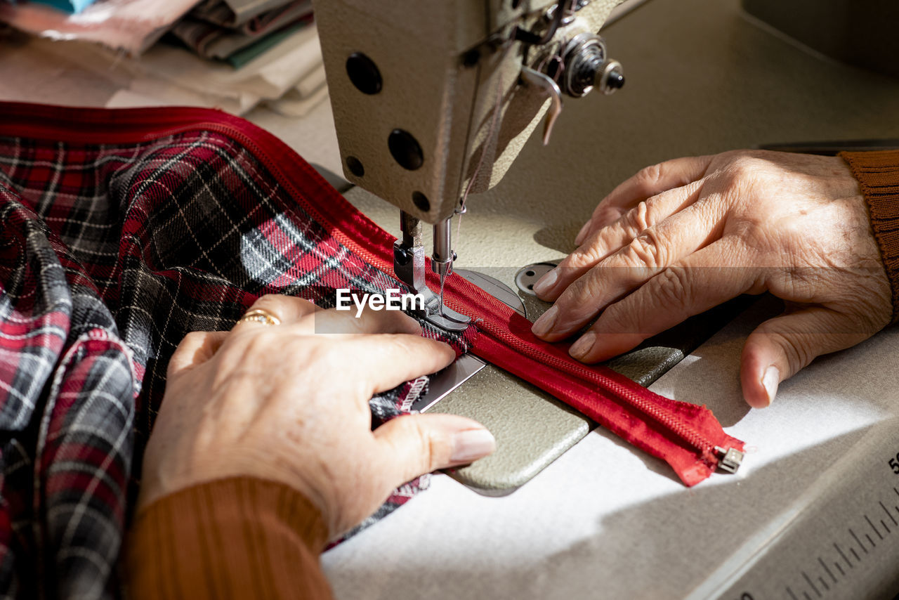 Close up of senior dressmaker hands sewing a zipper.