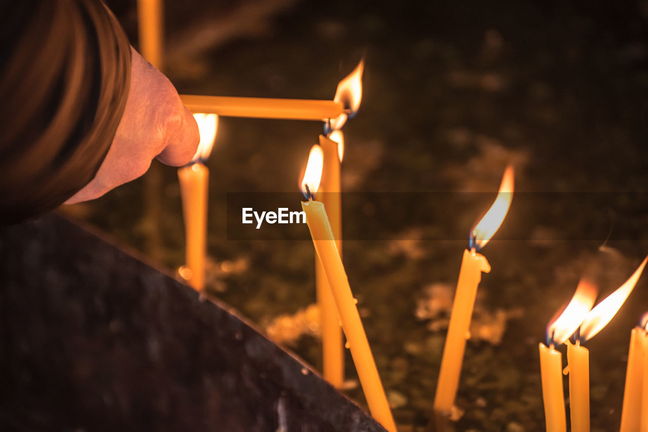 CLOSE-UP OF BURNING CANDLE AGAINST BLACK BACKGROUND