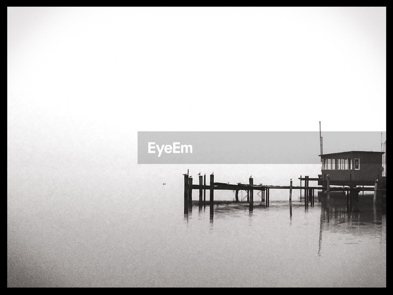 Hut on jetty in lake during foggy weather