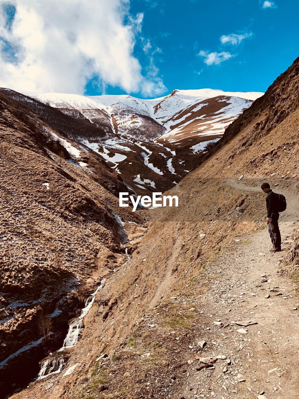 Side view of man standing on footpath against mountain