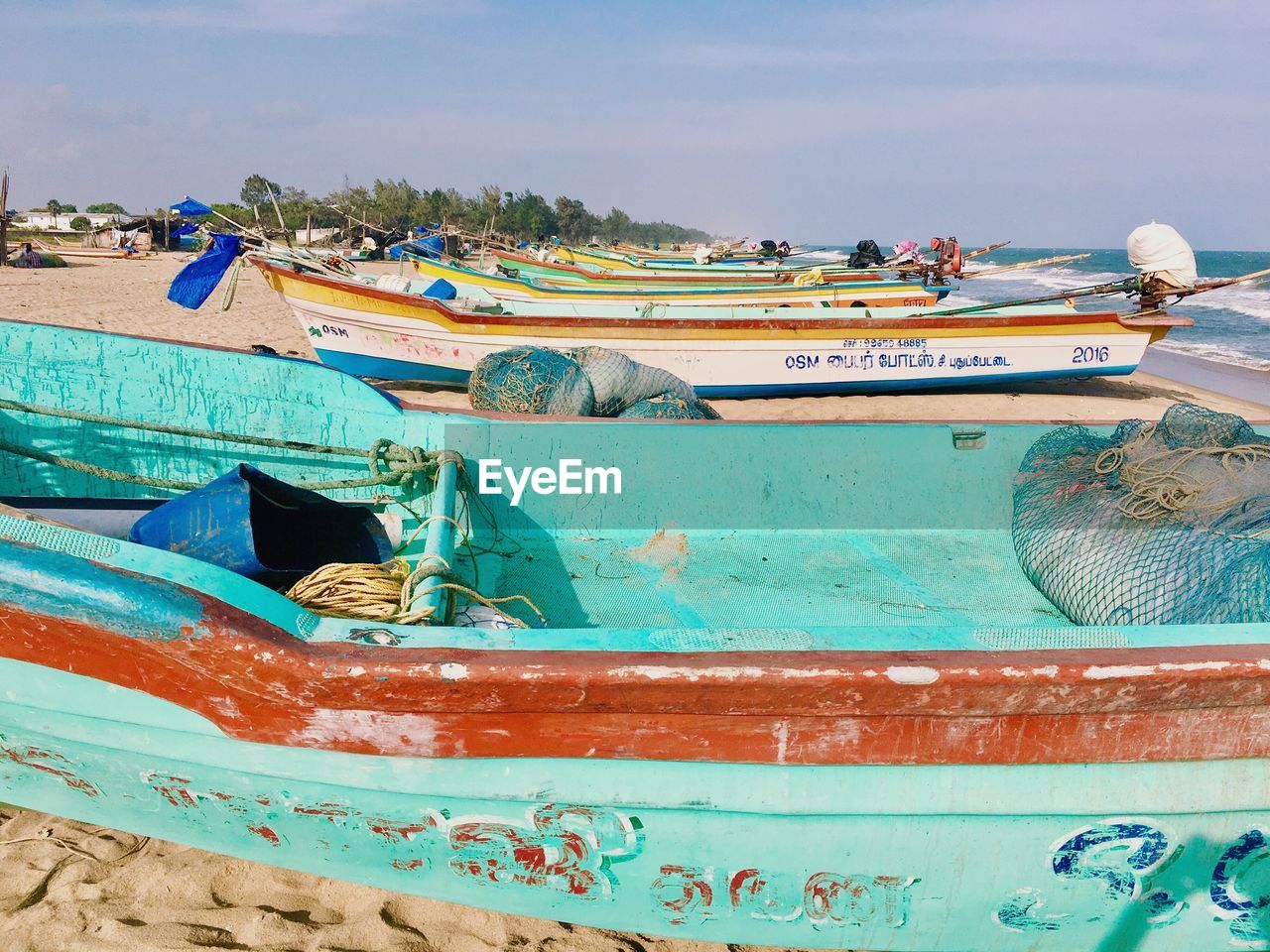 BOATS MOORED ON BEACH AGAINST SKY