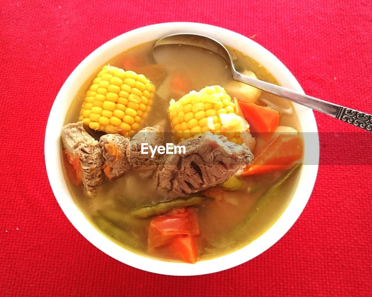 Directly above shot of soup in bowl on red table