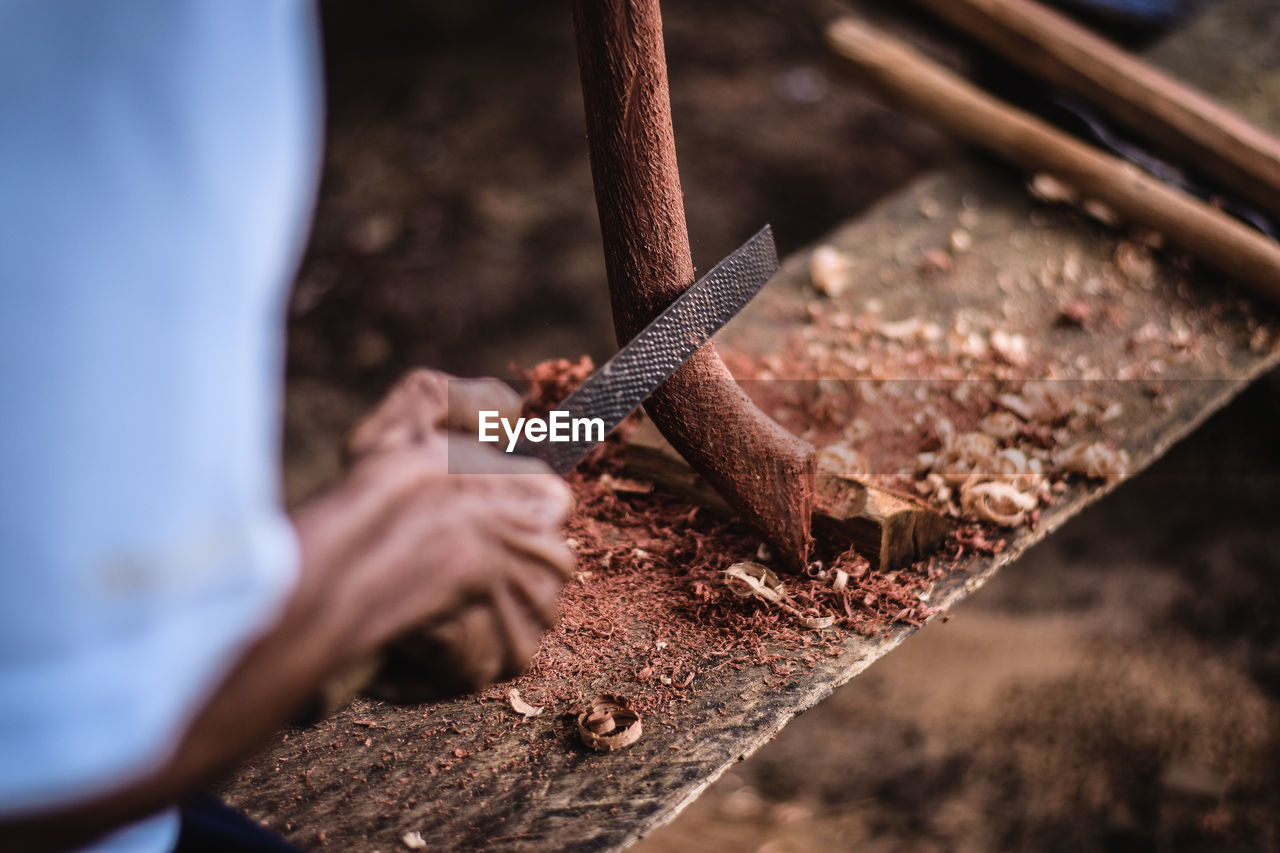 Midsection of worker shaving wood