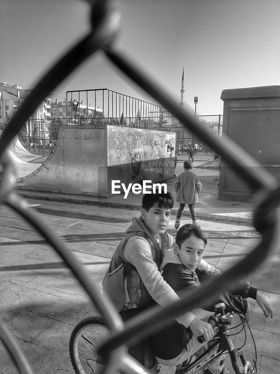 Boys riding on bicycle on road against sky