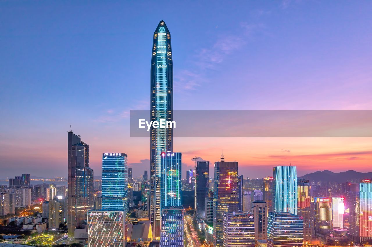 Illuminated modern buildings against sky during sunset