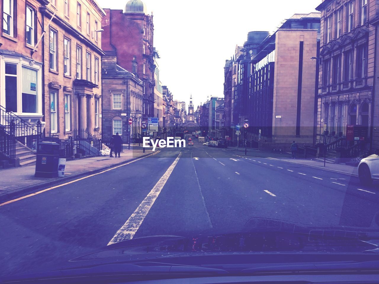 Road amidst buildings seen through car windshield