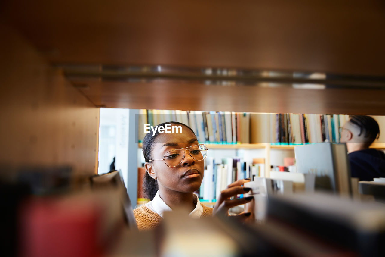 Male and female university students reading books in library