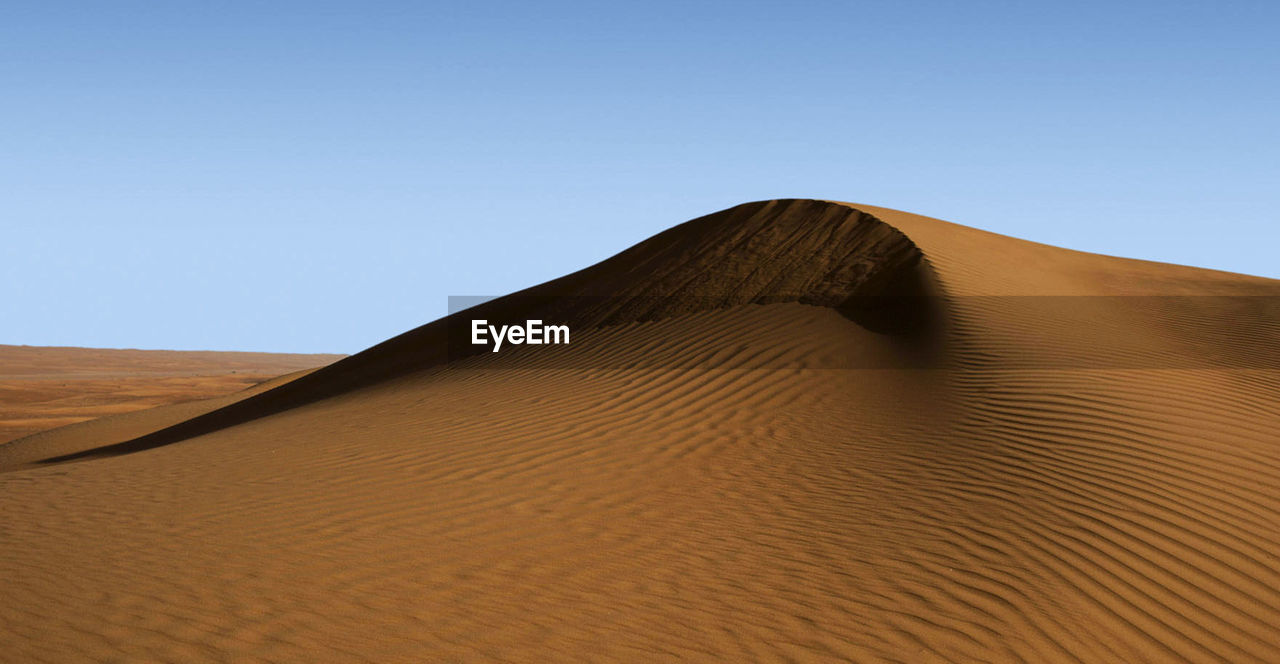 Sand dunes in desert against clear sky