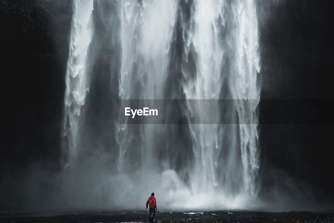 Rear view of man against waterfall