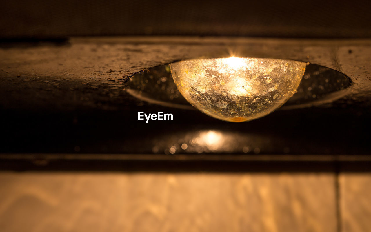 CLOSE-UP OF ILLUMINATED LIGHT BULB OVER WATER