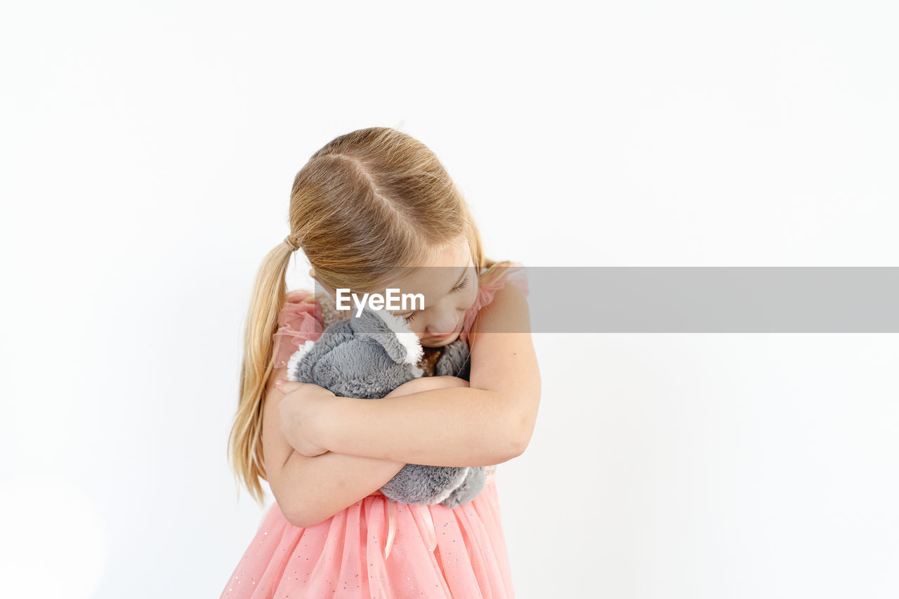 Blond little girl hugging koala stuffed animal indoors