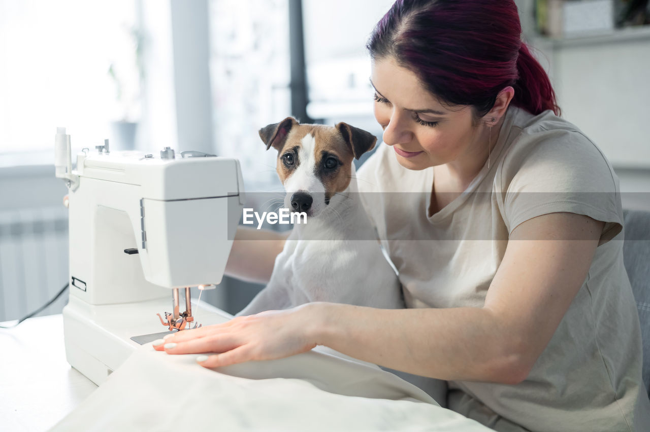 Midsection of woman with dog sitting on bed