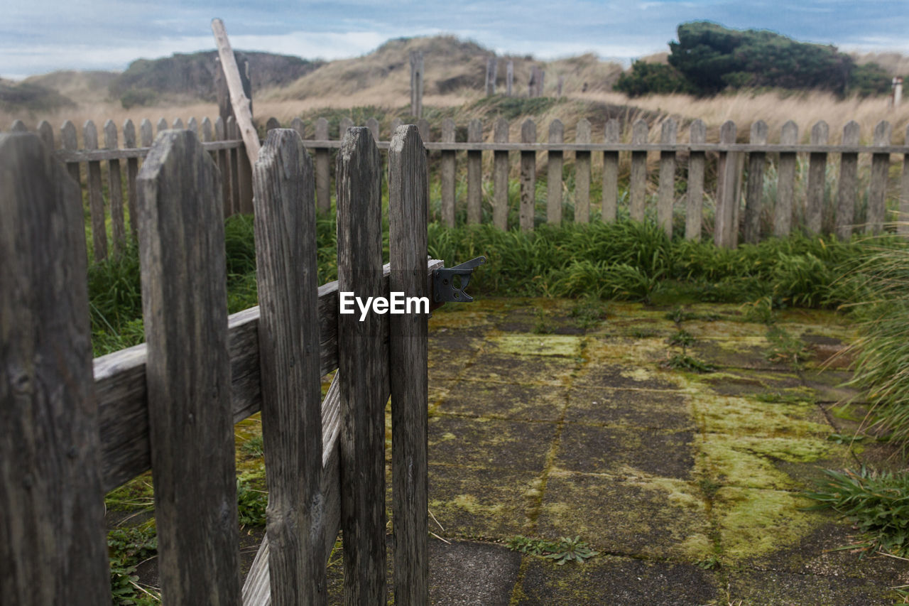 Wooden posts on landscape against sky