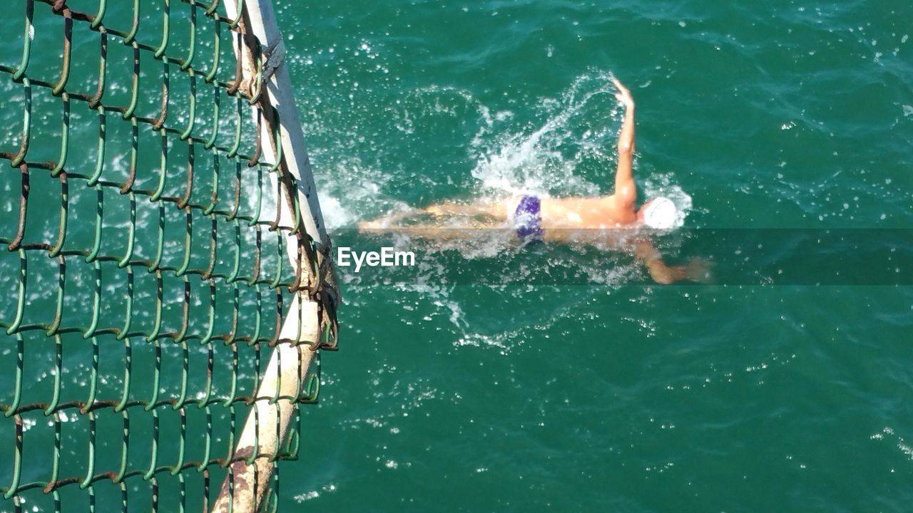 REFLECTION OF MAN SWIMMING IN WATER