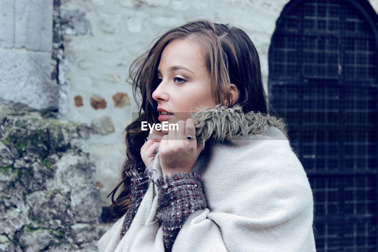 Woman looking away while standing in winter coat