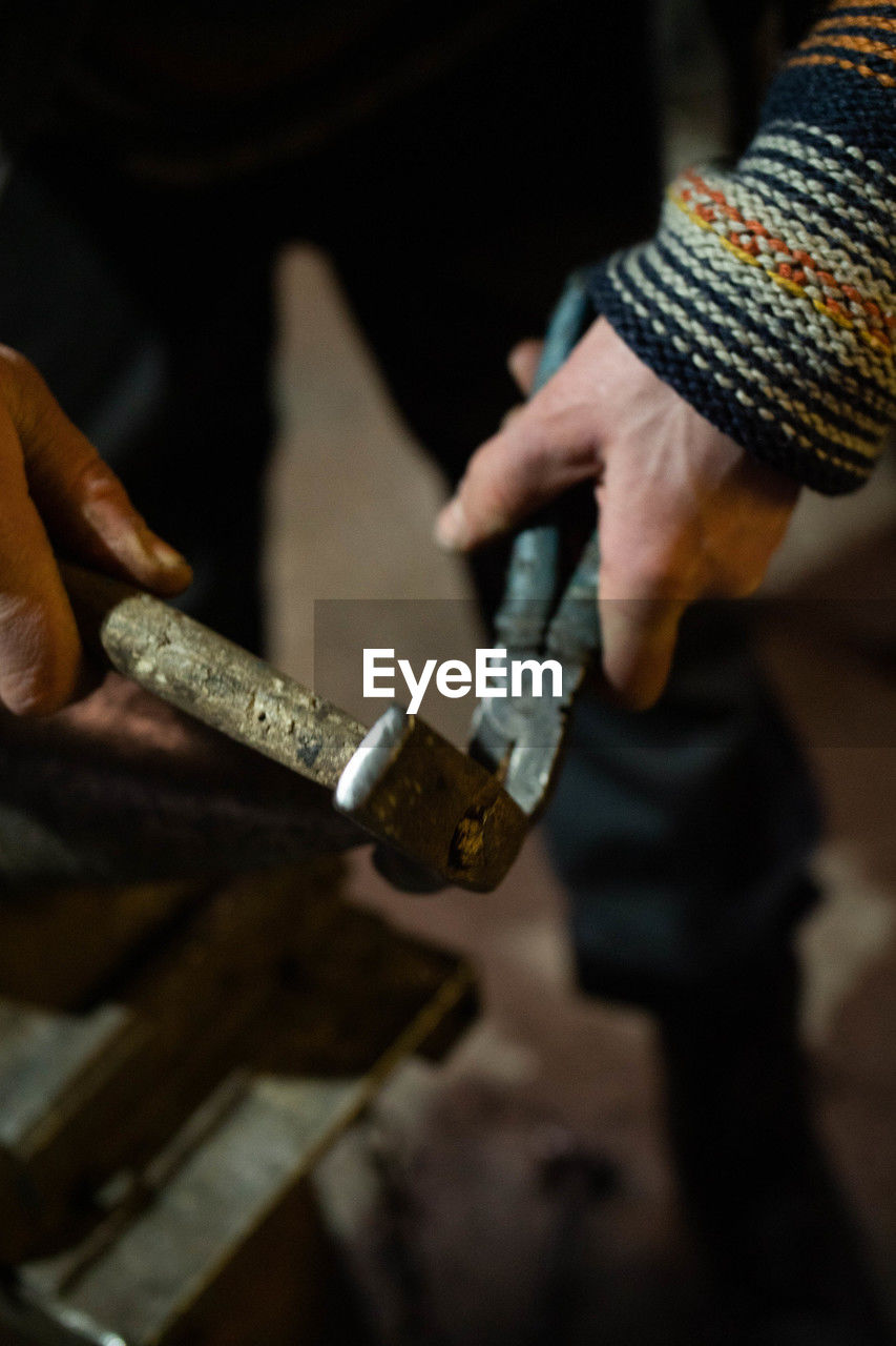 cropped hand of man working on metal