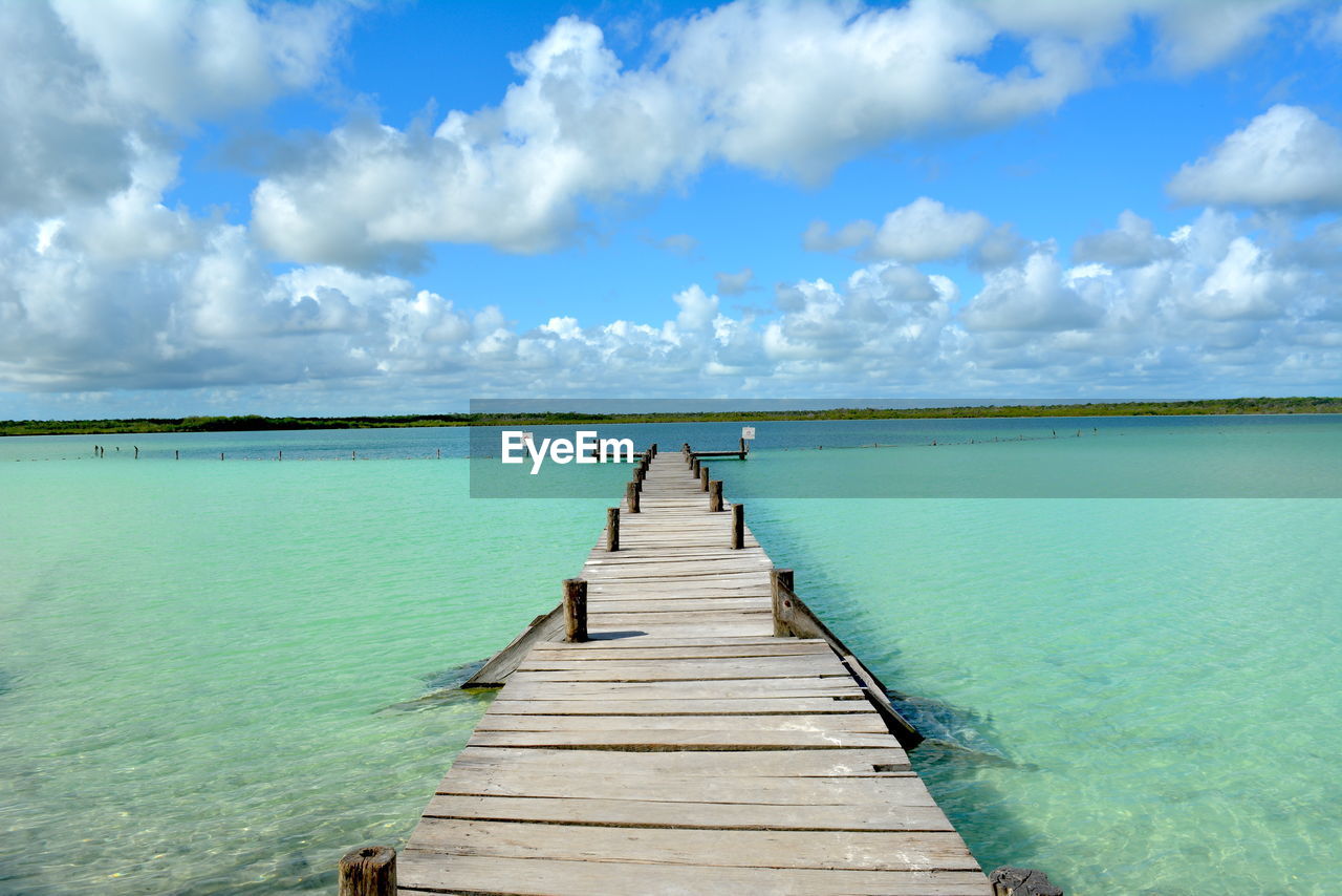 Wooden pier over sea against sky