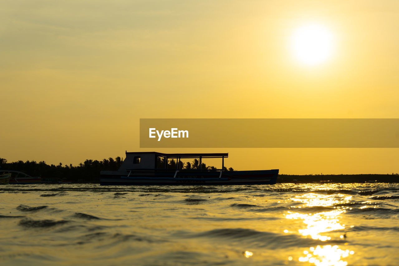 SILHOUETTE BOAT IN SEA AGAINST SKY DURING SUNSET