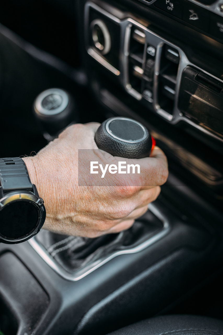 Crop view of anonymous man with her hand on the gear shift of an off-road car