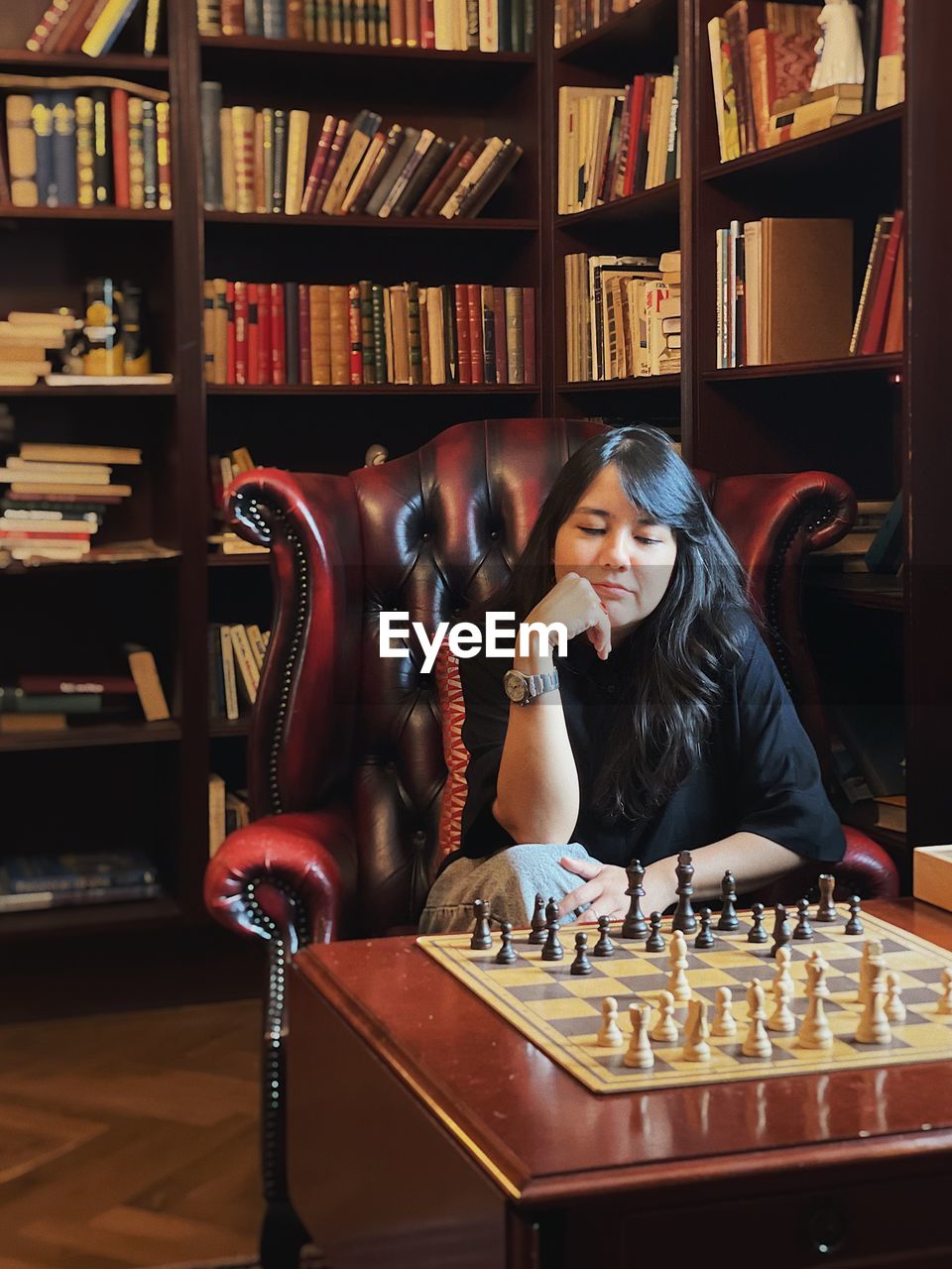 Full length of young woman sitting playing chess