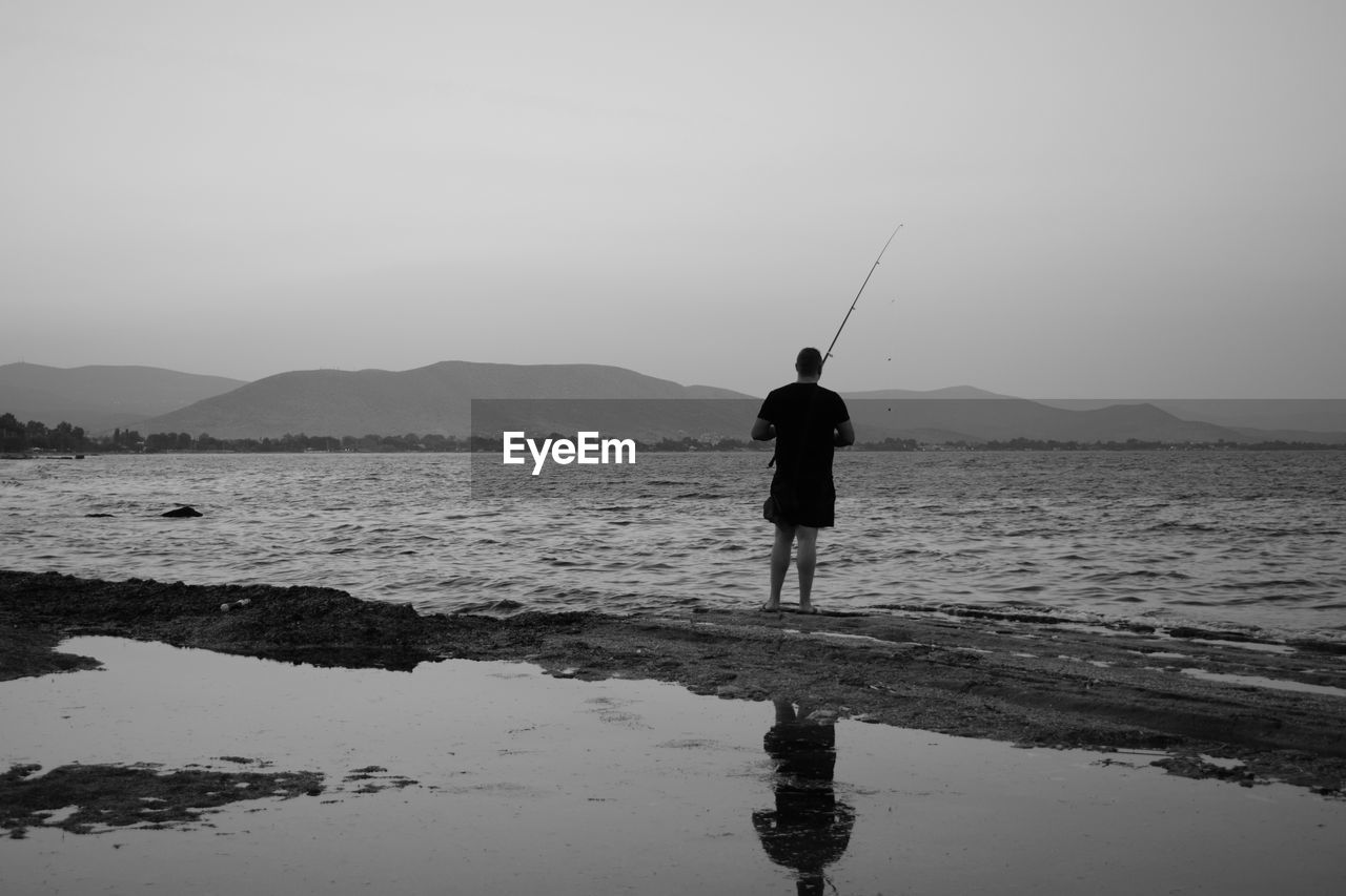 Rear view of man fishing in lake